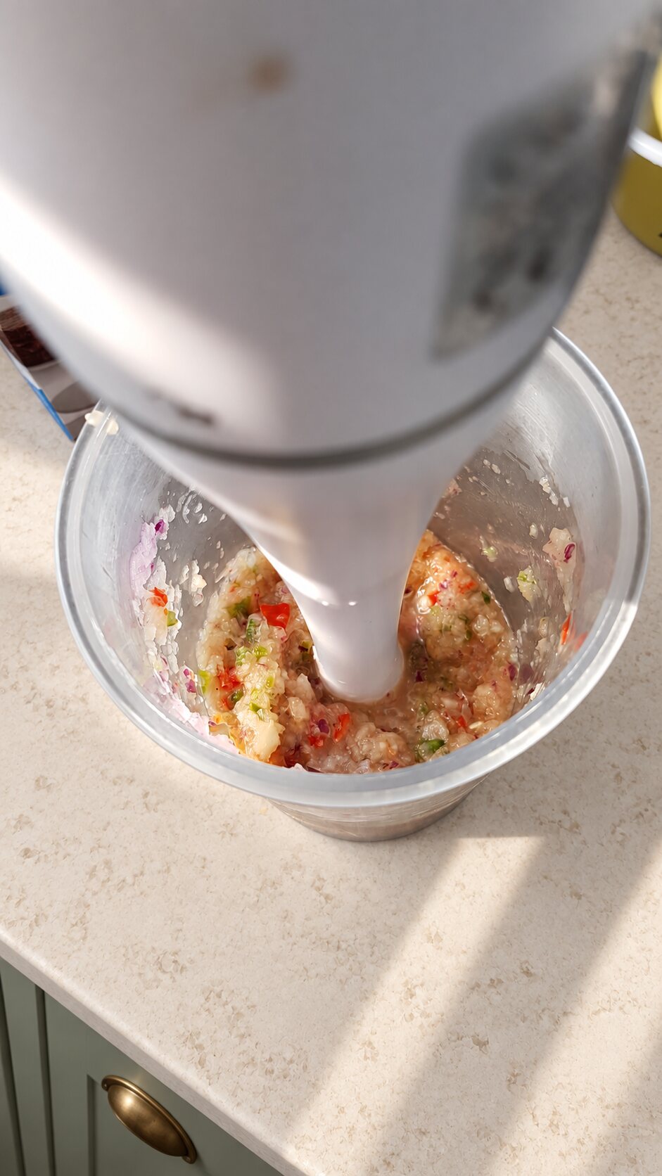 Onion, chilli, garlic and ginger being blended for homemade burgers on a pale kitchen worktop