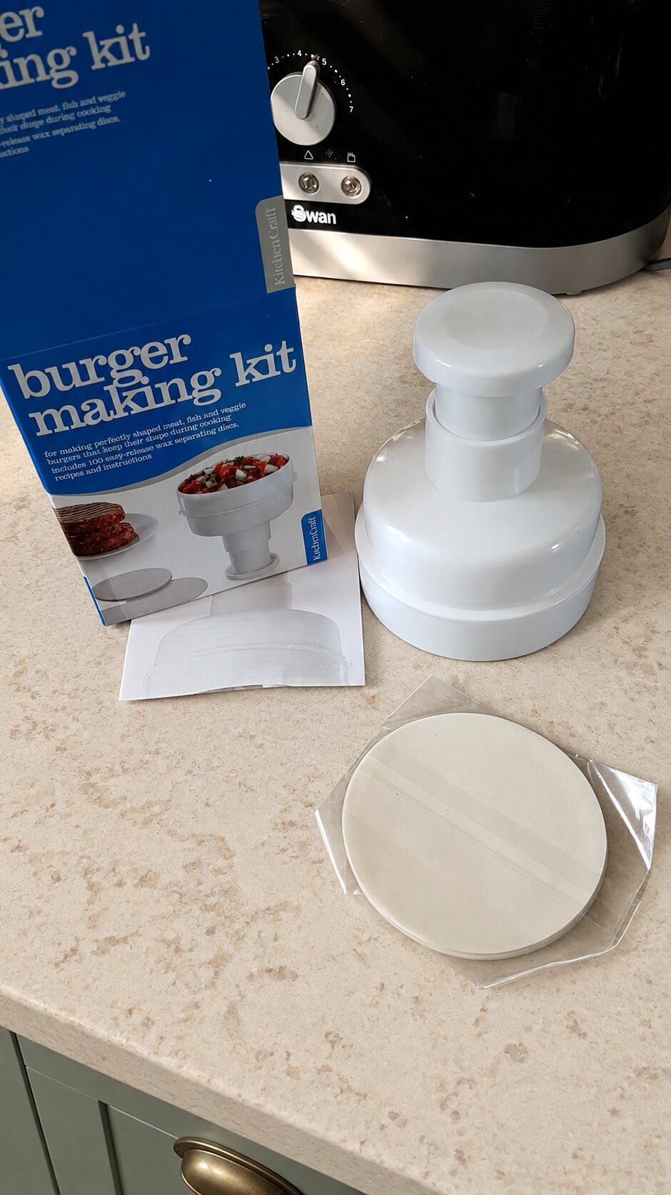 A burger press and separating papers on a pale stone worktop in the Foodwizardry showroom kitchen