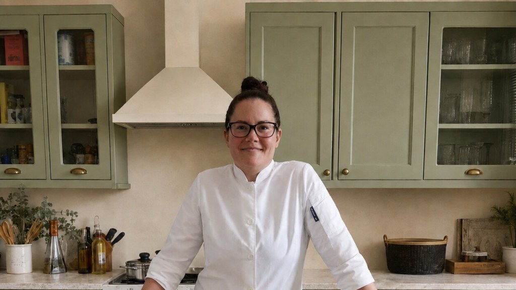 Catherine in her chef jacket in the sage-green Foodwizardry kitchen