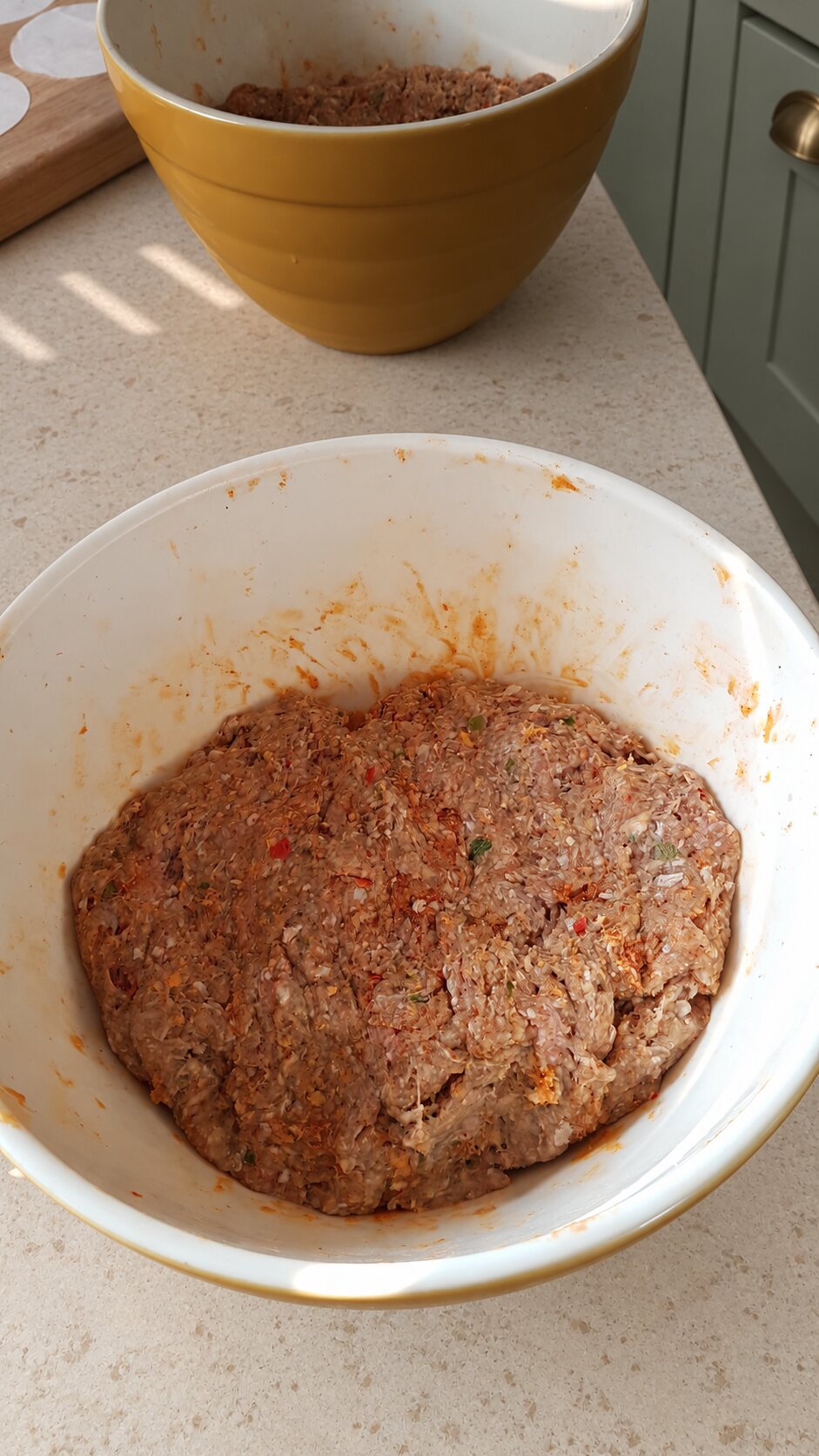 Seasoned beef burger mixture resting in a bowl on a pale stone worktop
