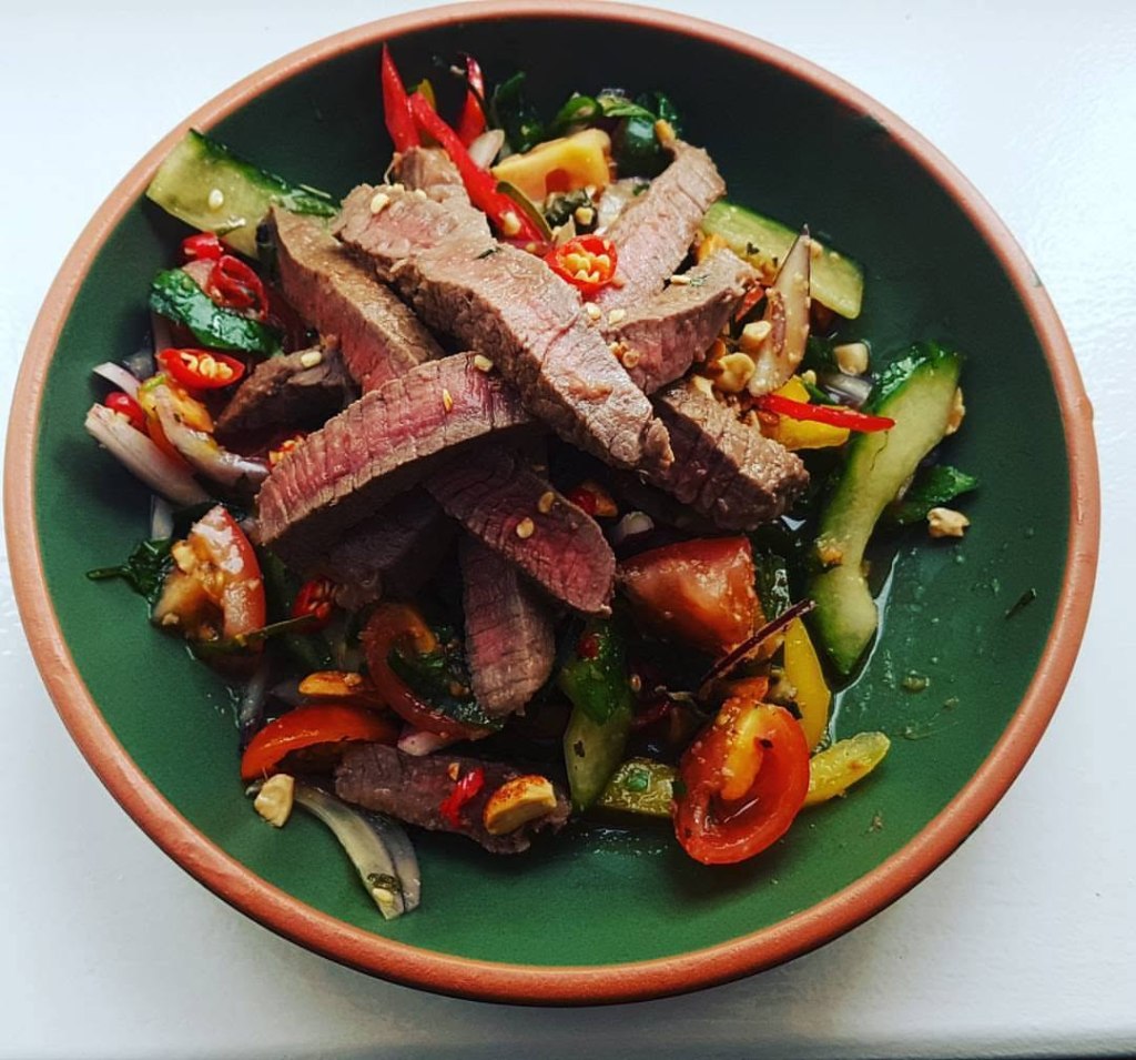 Yum Neua spicy Thai beef salad with rare steak, cucumber, tomatoes, peppers, herbs, chilli and crushed peanuts